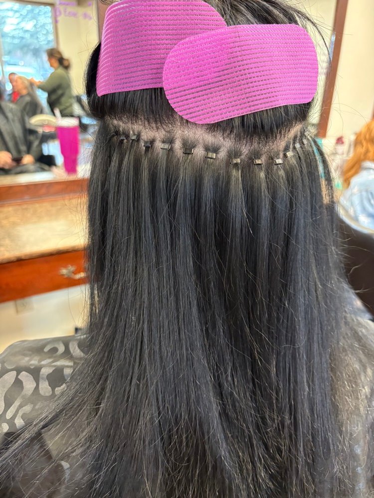 Sew-in weft extensions being installed on dark hair